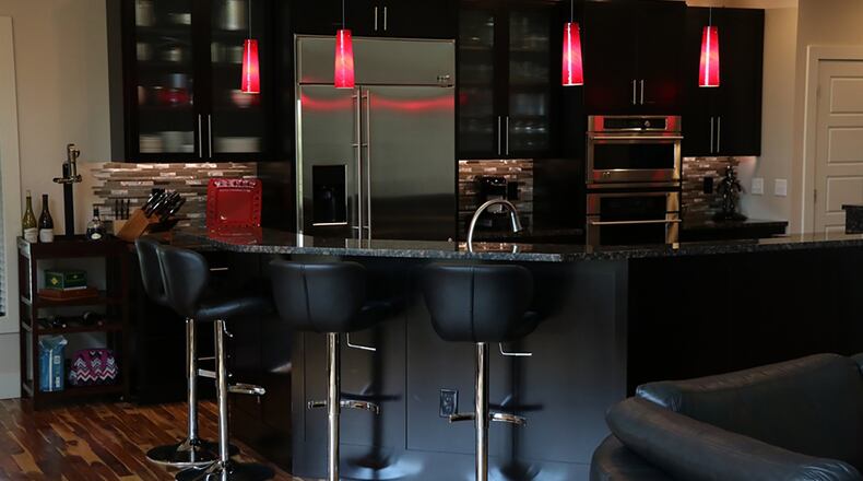 The open dining room connects directly to the sleek kitchen, which features oversized espresso-stained cabinets, granite counters and glass and metal miniature tile backsplashes. The five-sided island creates a semi-circle with a raised counter for bar seating and a lower work counter.