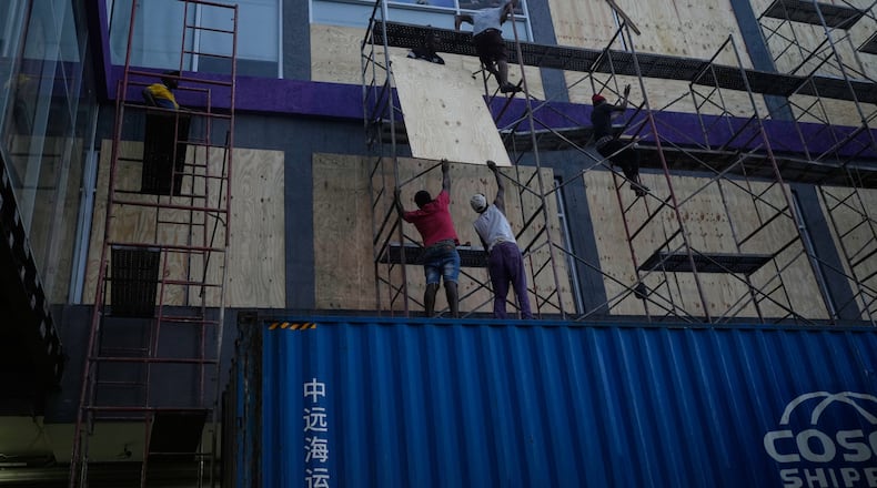 Workers board up shop windows ahead of Hurricane Melissa's forecast arrival in Kingston, Jamaica, Sunday, Oct. 26, 2025. (AP Photo/Matias Delacroix)