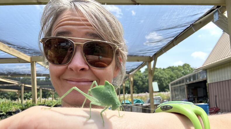 Deeply Rooted Landscapes owner Kara Maynard shows off a katydid, one of the many beneficiaries of the native gardens she creates. Contributed by Kara Maynard