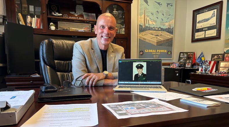 Col. Matthew Muha, deputy commander of the 445th Airlift Wing at Wright-Patterson Air Force Base, with a U.S. Army basic training photograph of his father, Thomas, who served during the Vietnam War. Muha is also director of the Autonomy Capability (ACT3) Team, at the Air Force Research Laboratory, also at Wright-Patterson. THOMAS GNAU/STAFF