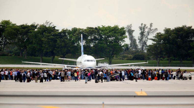 People stand on the tarmac at the Fort Lauderdale-Hollywood International Airport after a shooter opened fire inside a terminal of the airport, killing several people and wounding others before being taken into custody, Friday, Jan. 6, 2017, in Fort Lauderdale, Fla. (Al Diaz /Miami Herald via AP)