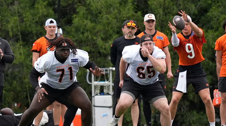 Cincinnati Bengals tackle Amarius Mims (71) and guard Alex Cappa (65) run a play as quarterback Joe Burrow (9) takes a snap from the center during the NFL football team's practice on Tuesday, May 14, 2024, in Cincinnati. (AP Photo/Carolyn Kaster)