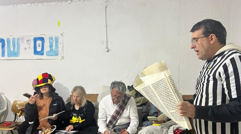 Dov Rabinowitz reads the biblical Book of Esther aloud to guests in his Jerusalem home. ELYSSA MOSS RABINOWITZ/CONTRIBUTED