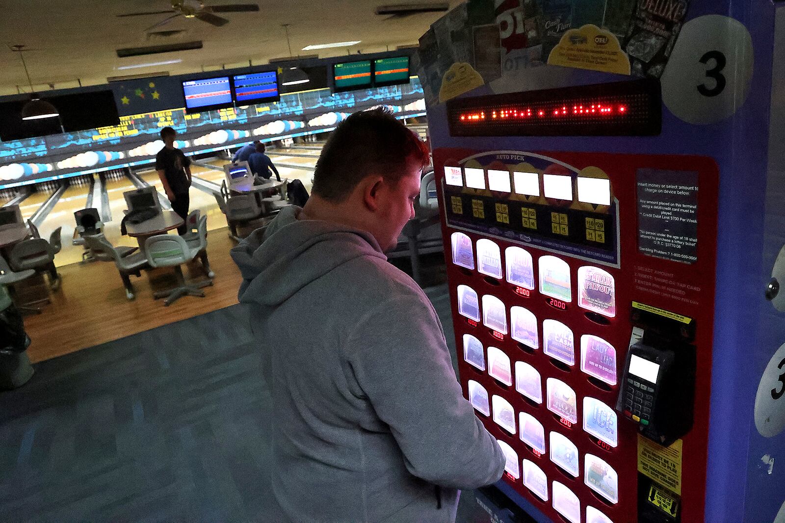 Brandon Oty looks over the Ohio Lottery instant games in a kiosk at Victory Lanes bowling alley in Springfield. BILL LACKEY/STAFF