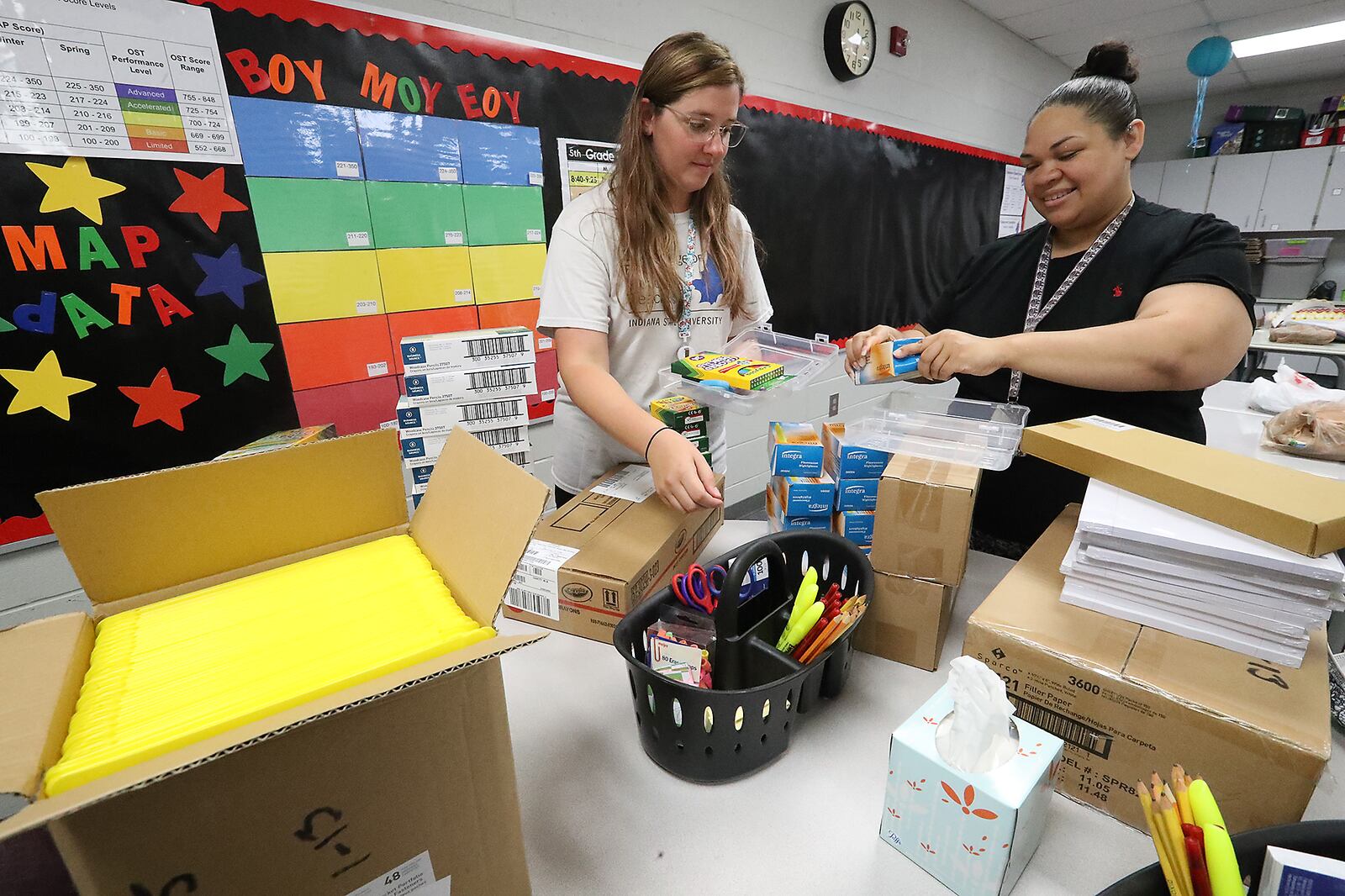 Fulton Elementary School teacher's Mikyla Timmerman, left, and Kathleen Haley put school supplies, provided by the Springfield School District, into plastic boxes for each student Tuesday as they prepare for school to start Wednesday. BILL LACKEY/STAFF