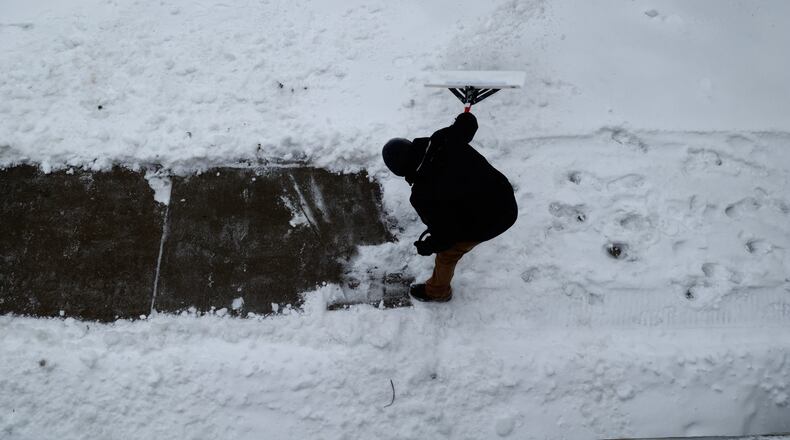 A man is seen from above as he shovels snow off the sidewalk along Jefferson Street Friday.