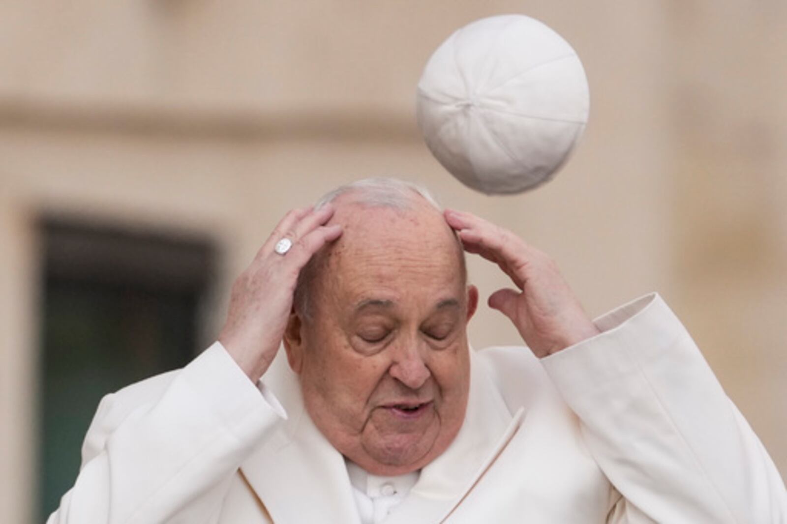 FILE - Pope Francis tries to catch his cap as wind blew it away while arriving for his weekly general audience in the St. Peter's Square at the Vatican, Wednesday, March 13, 2024. (AP Photo/Andrew Medichini, File)