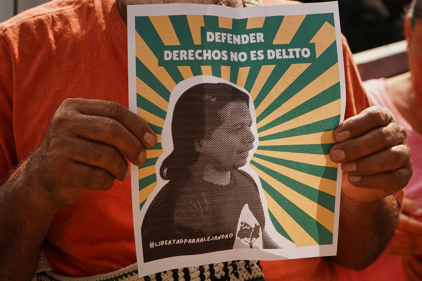 A man holds a poster of Alejandro Henriquez outside the courts during their hearing in Santa Tecla, El Salvador, Friday, May 30, 2025. The National Civil Police arrested them for protesting near the presidnetial residence. (AP Photo/Salvador Melendez)