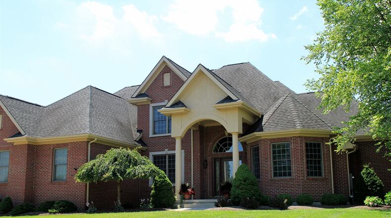 Brick construction, bay windows and a covered entrance framed with an arch and round columns create a stately facade for this 2-story brick home in Washington Twp. Landscaping of the front flowerbeds include a weeping cherry tree, a birch tree and evergreens in varying shapes. CONTRIBUTED PHOTOS BY KATHY TYLER