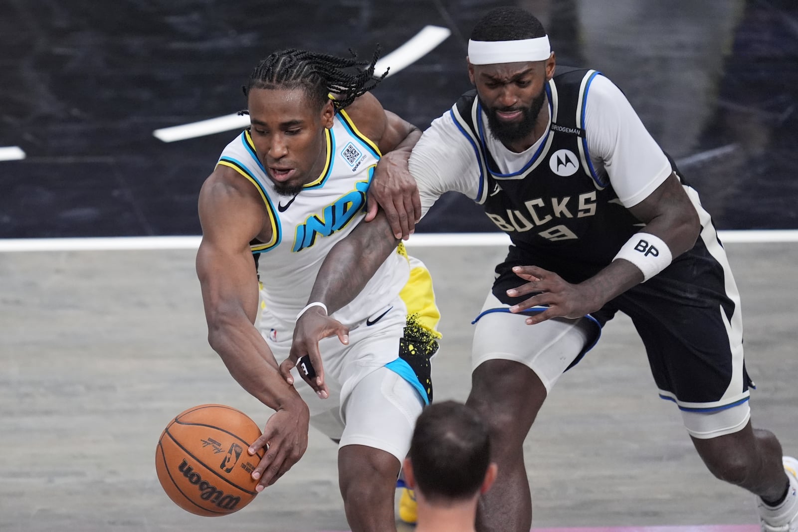 Indiana Pacers forward Aaron Nesmith, left, chases the ball past Milwaukee Bucks forward Bobby Portis (9) during overtime in Game 5 of an NBA basketball first-round playoff series in Indianapolis, Tuesday, April 29, 2025. (AP Photo/Michael Conroy)