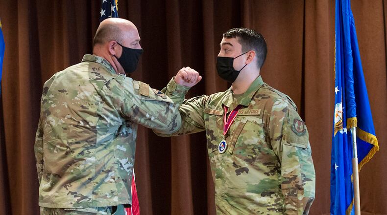 Col. Patrick Miller (left), 88th Air Base Wing and installation commander, elbow-bumps Staff Sgt. Marc Lejeune during the Airman Leadership School Class 21-C graduation ceremony March 25 at Wright-Patterson Air Force Base. Miller recognized and presented a coin to Lejeune for initiating basic first aid to a neighbor March 23. U.S. AIR FORCE PHOTO/WESLEY FARNSWORTH