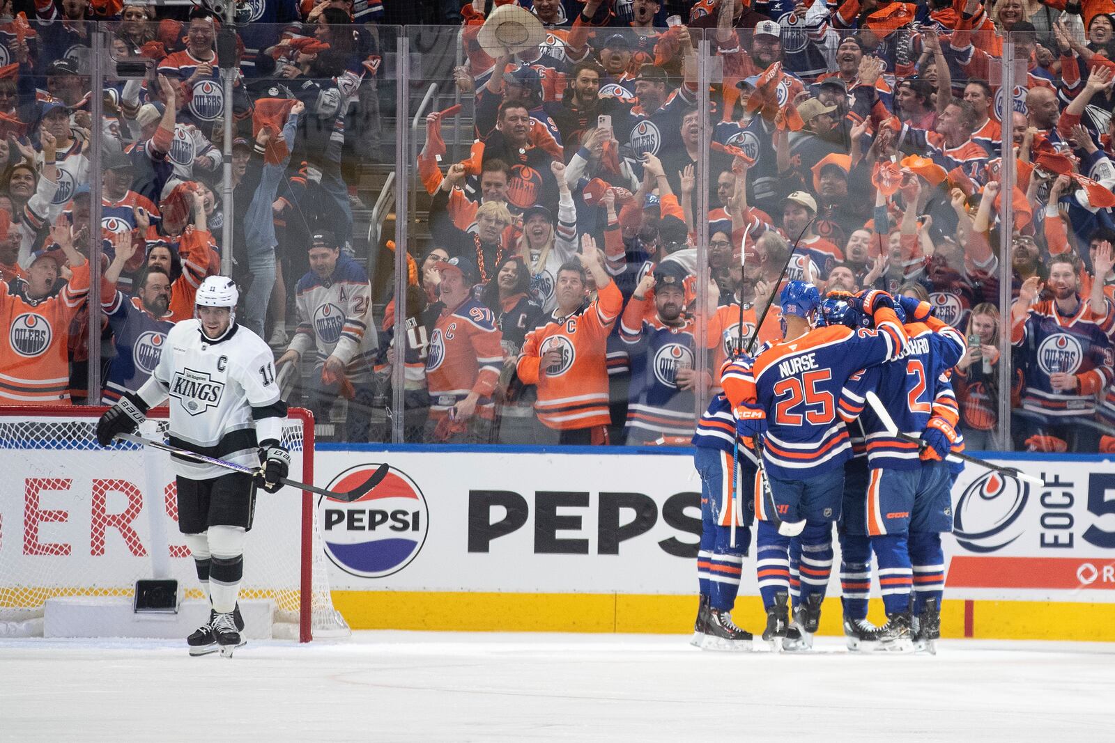 Los Angeles Kings' Anze Kopitar (11) skates past as the Edmonton Oilers celebrate after a goal during the first period of Game 3 of a first-round NHL hockey playoff series in Edmonton, Alberta, Friday, April 25, 2025. (Jason Franson/The Canadian Press via AP)