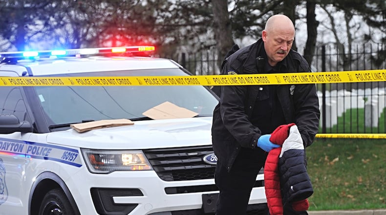 A member of the Dayton Police Division processes evidence along West Third Street near the Westown Shopping Center where a man was shot Wednesday. MARSHALL GORBYSTAFF