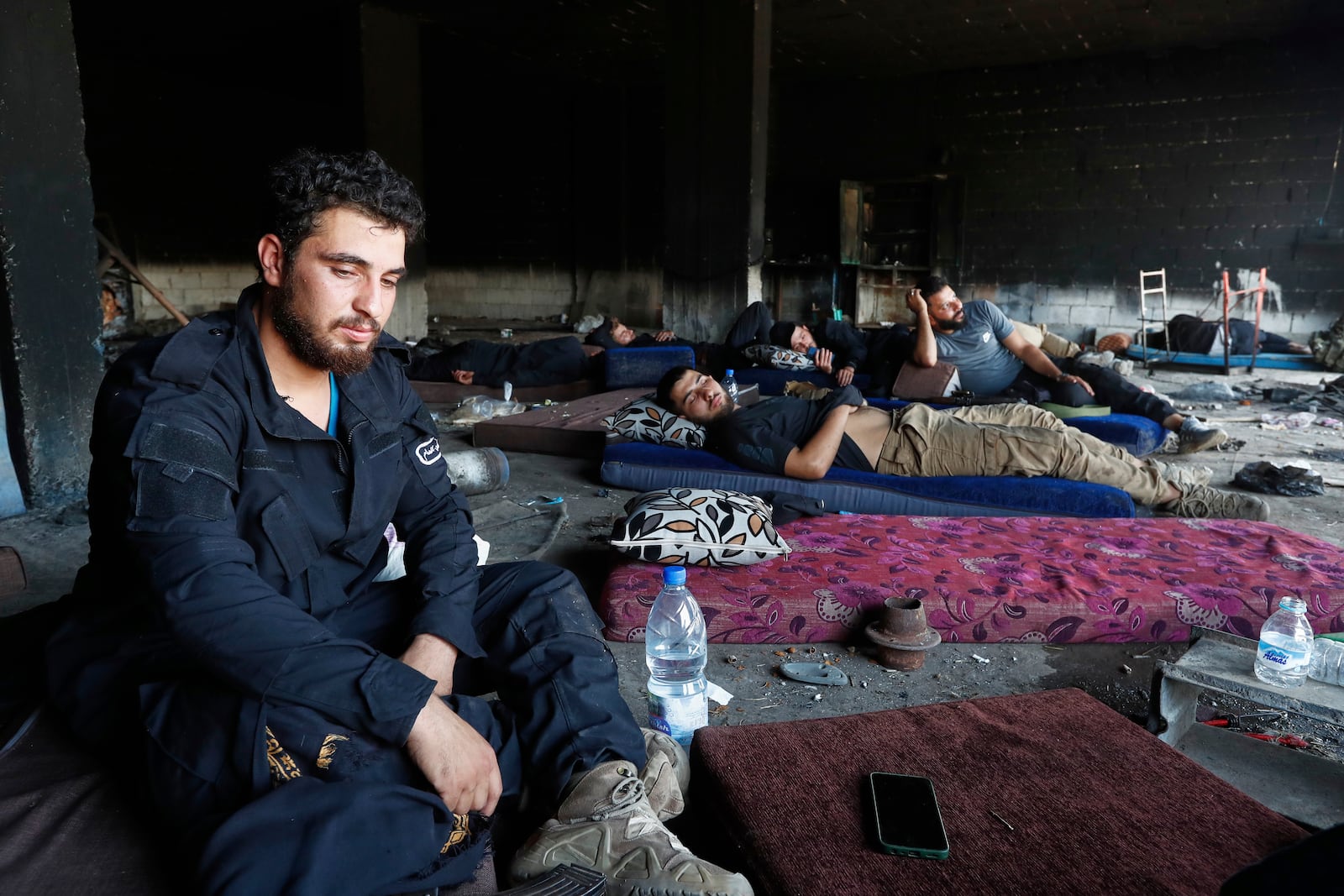 Syrian security forces rest inside a burned out shop as they deploy in Mazraa village on the outskirts of Sweida city, in southern Syria, Sunday, July 20, 2025. (AP Photo/Omar Sanadiki)