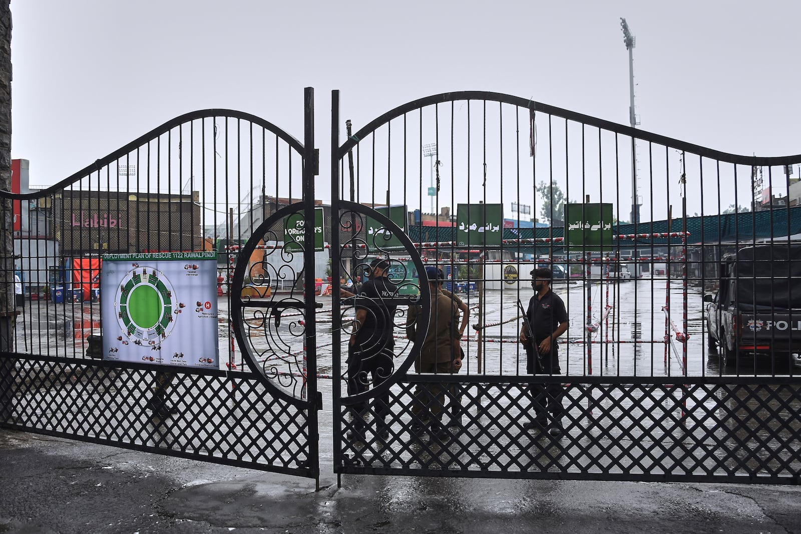 Police officers stand guard behind a closed gate of an entry point to Pindi Cricket Stadium following a suspected Indian drones crashed in the parking area, in Rawalpindi, Pakistan, Thursday, May 8, 2025. (AP Photo/W.K. Youszai)