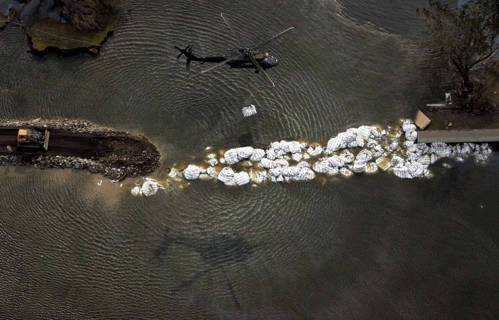 FILE - A military helicopter drops a sandbag as work continues to repair the 17th Street canal levee in New Orleans, Sept. 5, 2005. (AP Photo/David J. Phillip, Pool, File)