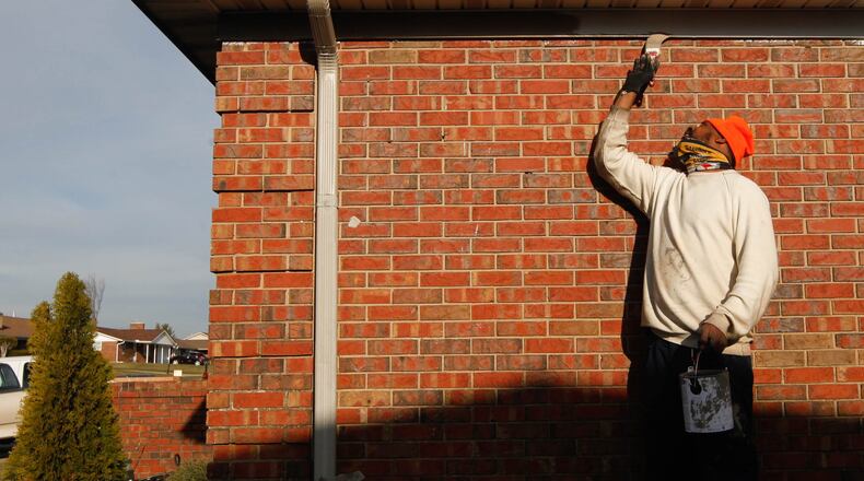 Errick Potter paints one of three tornado damaged houses he has been working to repair on Berquist Drive in Trotwood. This house received new exterior brick and a new roof. Repairs to homes since the 2019  Memorial Day tornadoes have brought back $26.8 million of $85 million in lost property values. CHRIS STEWART / STAFF