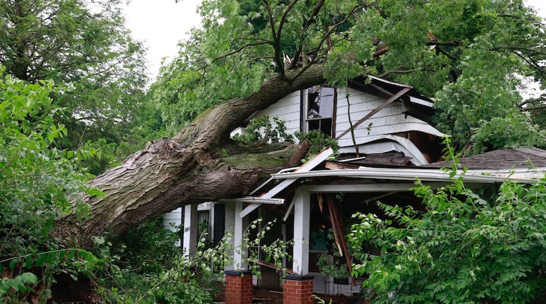 A tree fell on a vacant house on Lincoln Street in Christiansburg in Champaign County on Sunday. Crews were in the village to clean up damage on Monday, June 12, 2023. BILL LACKEY/STAFF