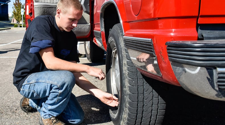 Gage Hacker, a Hamilton High School junior in the Career Technical Education Automotive Technology program, checks tire pressure on a student vehicle as students and AAA team up for safety checks on cars Tuesday, Oct. 3 at Hamilton High School in Hamilton. NICK GRAHAM/STAFF