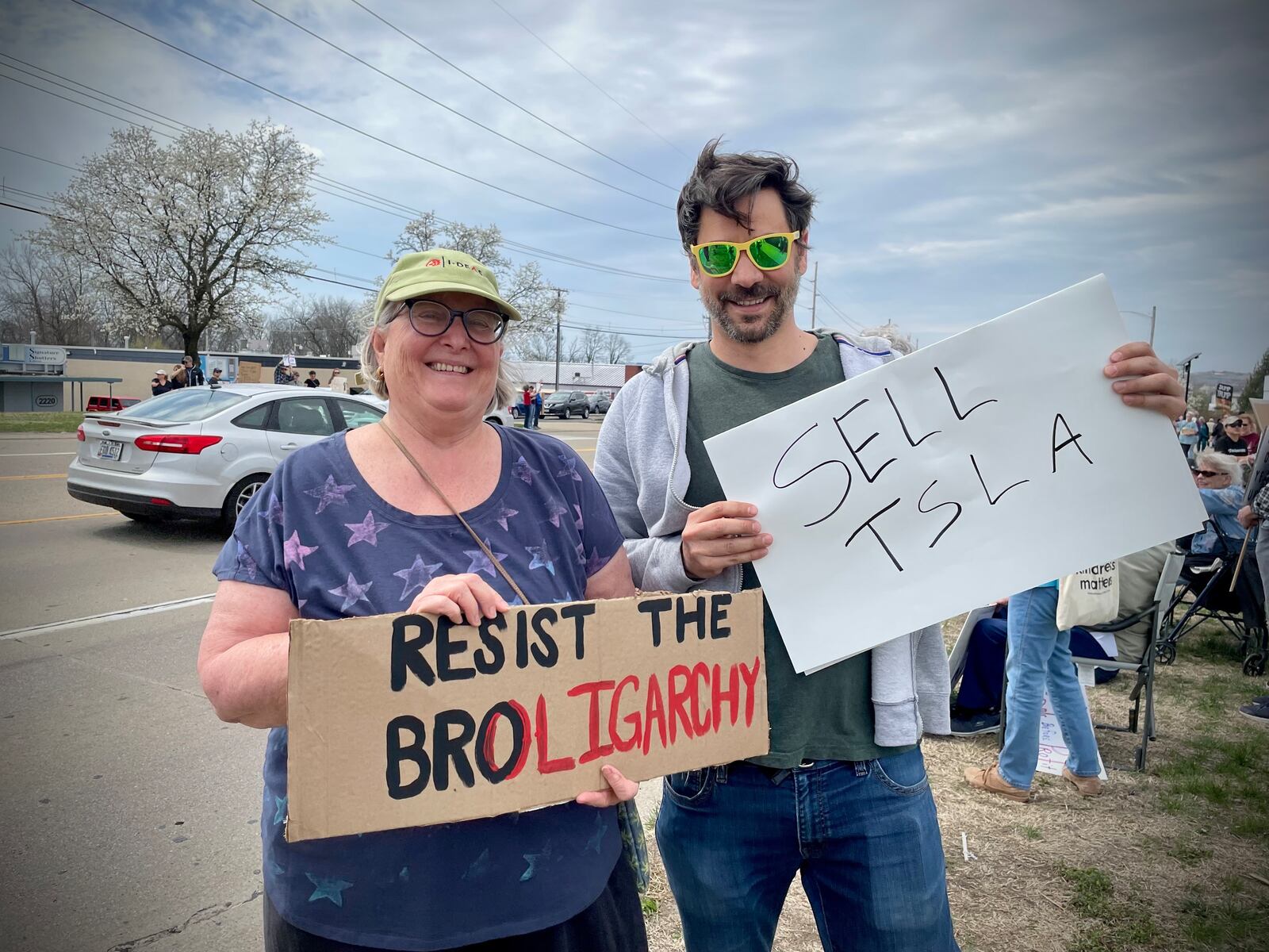 A crowd of more than 100 people lined both sides of West Dorothy Lane in front of the Tesla Service Center in Moraine on Saturday, March 29 as part of a nationwide “Tesla Takedown” movement. Pictured (right) is John Apesos of Centerville. NATALIE JONES/STAFF