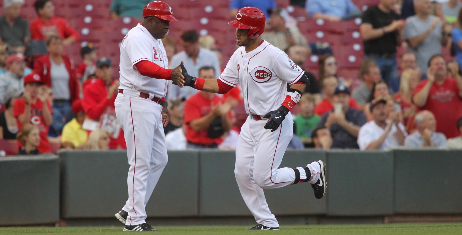 The Reds’ Eugenio Suarez, right, slaps hands with third-base coach Billy Hatcher after a home run against the Brewers on Tuesday, June 27, 2017, at Great American Ball Park in Cincinnati.