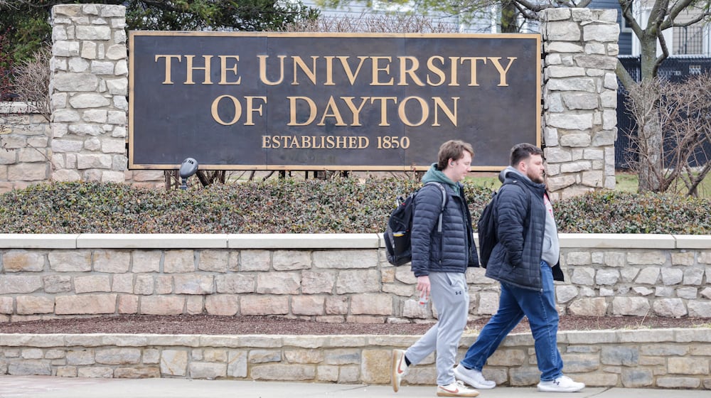 Two men walk by a University of Dayton sign on East Stewart Street on Monday, March 2. BRYANT BILLING / STAFF