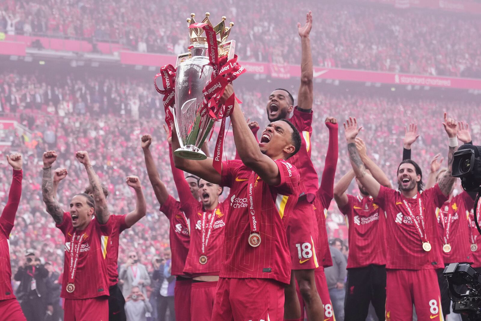 Liverpool's Trent Alexander-Arnold holds the winner's trophy as he celebrates with teammates after the English Premier League soccer match between Liverpool and Crystal Palace at the Anfield stadium in Liverpool, England, Sunday, May 25, 2025. (AP Photo/Jon Super)
