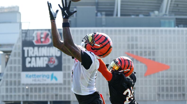 Cincinnati Bengals' Tee Higgins, left, makes a catch ahead of Cam Taylor-Britt (29) during practice at the team's NFL football training camp, Thursday, July 24, 2025, in Cincinnati. (AP Photo/Jeff Dean)