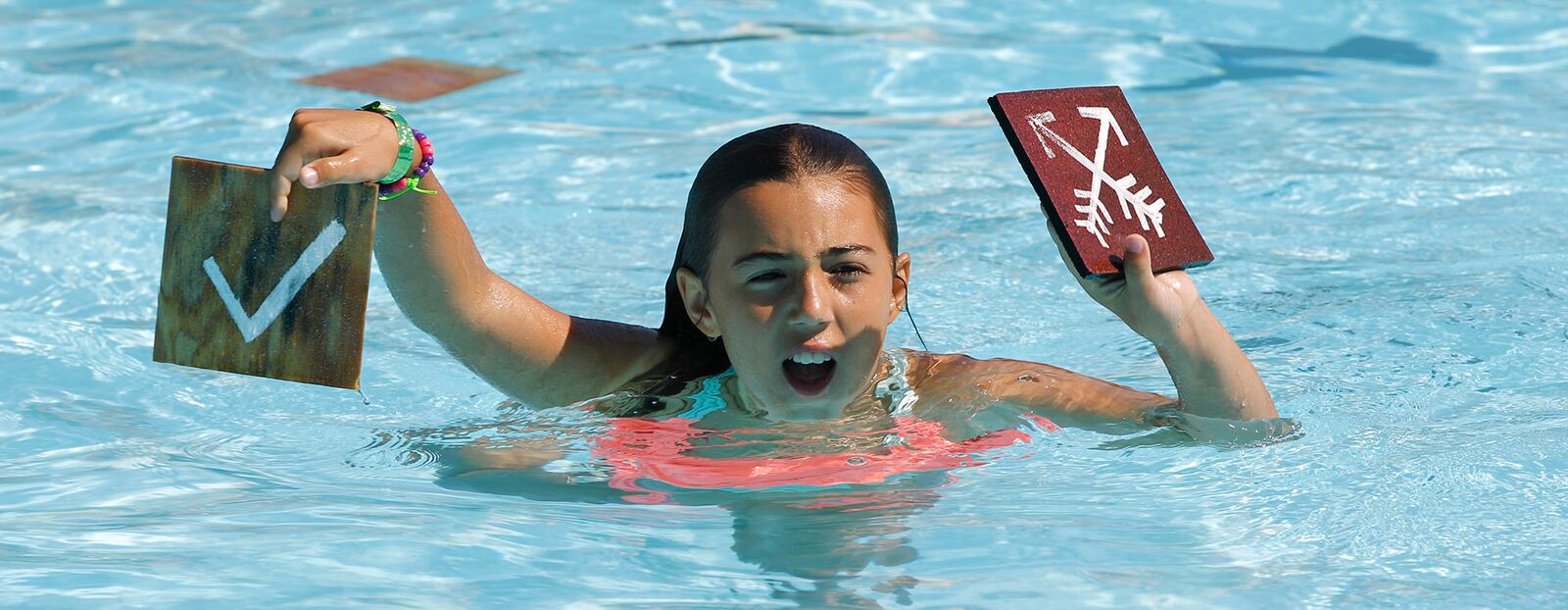 Camper Kathryn Zervos displays tiles for her teammates during a swimming game at Camp Kern.   TY GREENLEES / STAFF
