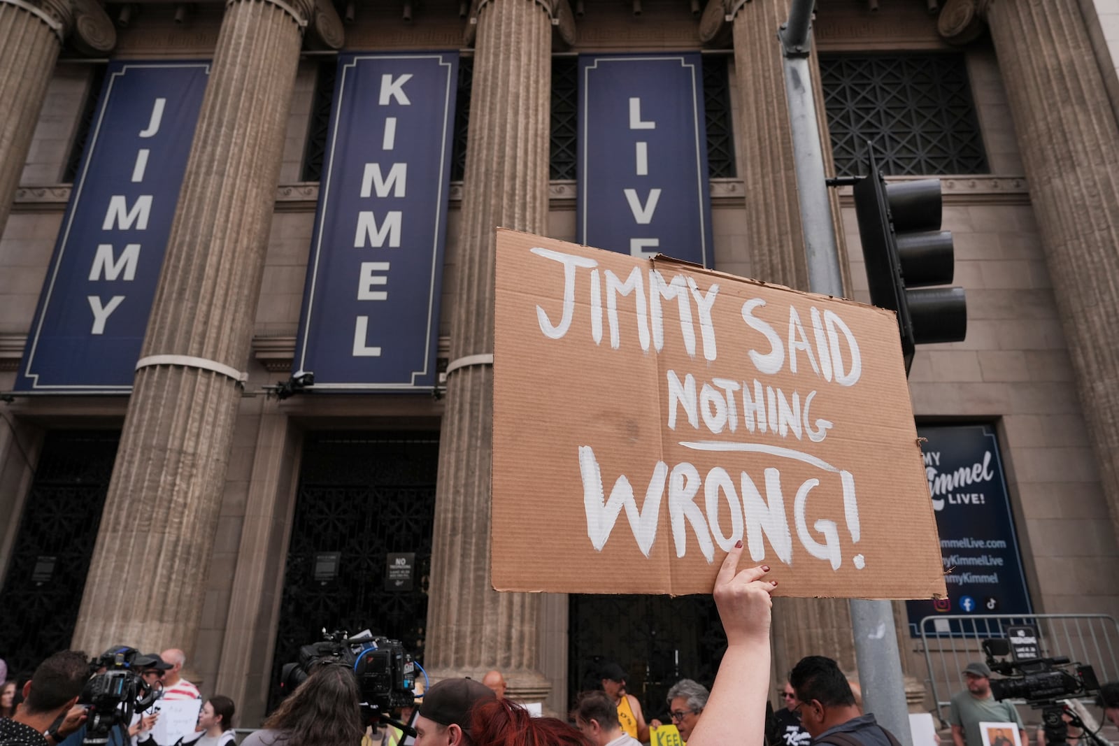 Demonstrators hold signs outside El Capitan Entertainment Centre, where the late-night show "Jimmy Kimmel Live!" is staged, Thursday, Sept. 18, 2025, in Los Angeles. (AP Photo/Jae C. Hong)