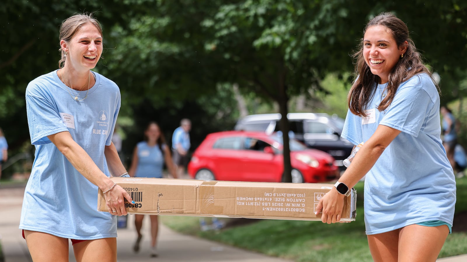 University of Dayton student Camille Shiffer (left) and Sarah Khalil laugh while moving a box on Friday, Aug. 22, in front of Marycrest Hall. The two were among dozens of volunteers meeting freshmen in front of the building and helping them move in. The university is welcoming about 1,700 freshmen this weekend. BRYANT BILLING / STAFF