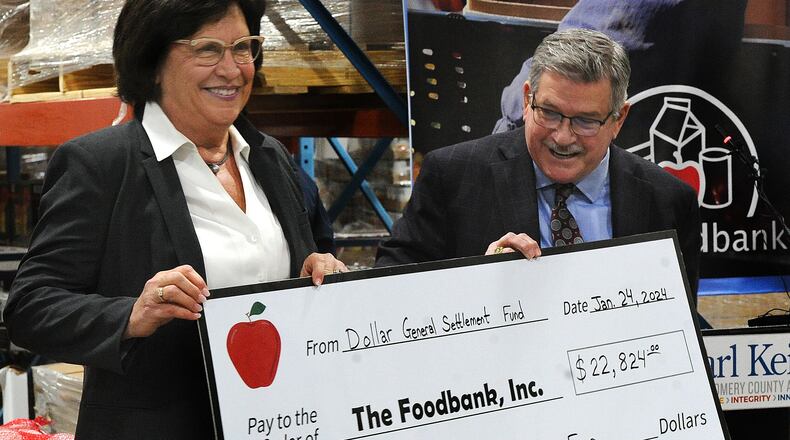 Foodbank Inc. CEO Michelle Riley and Montgomery County Auditor Karl Keith hold up a check Wednesday, Jan. 24, 2024 that represents the Dollar General settlement money passed along to the foodbank network on Dec. 24, 2023. MARSHALL GORBY\STAFF