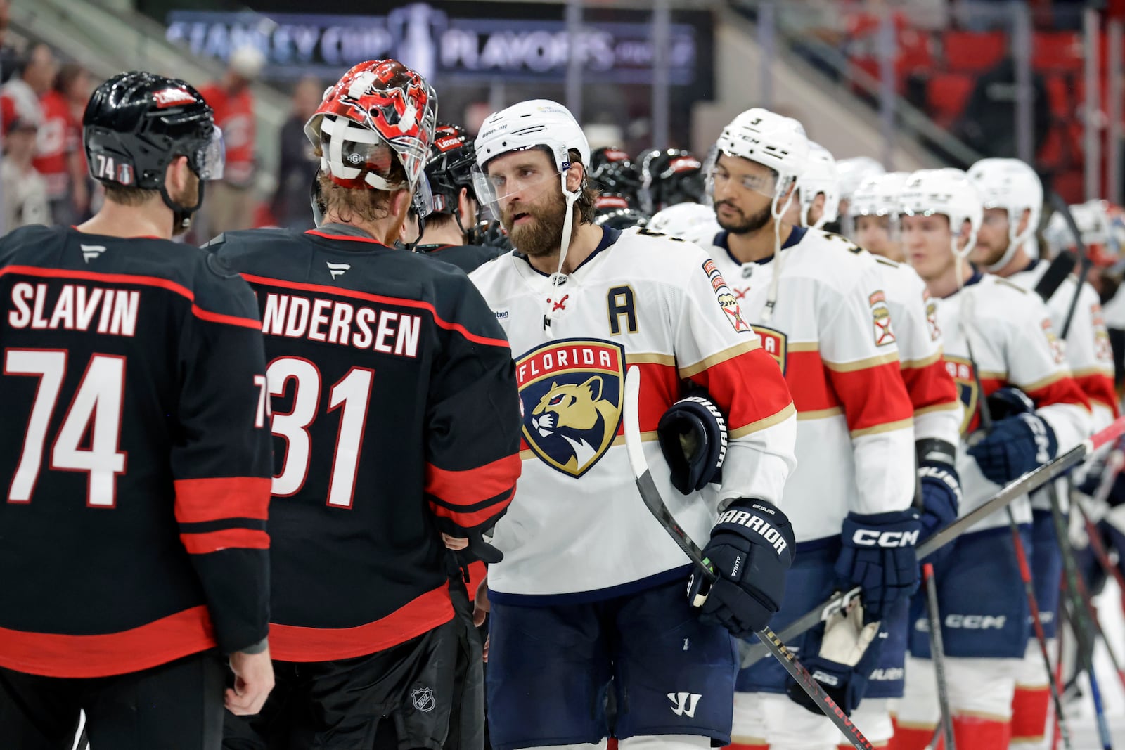 Florida Panthers defenseman Aaron Ekblad (A) shakes hands with Carolina Hurricanes goaltender Frederik Andersen (31) and Carolina Hurricanes defenseman Jaccob Slavin (74) at the end of Game 5 of the NHL hockey Stanley Cup Eastern Conference finals Wednesday, May 28, 2025, in Raleigh, N.C. (AP Photo/Chris Seward)