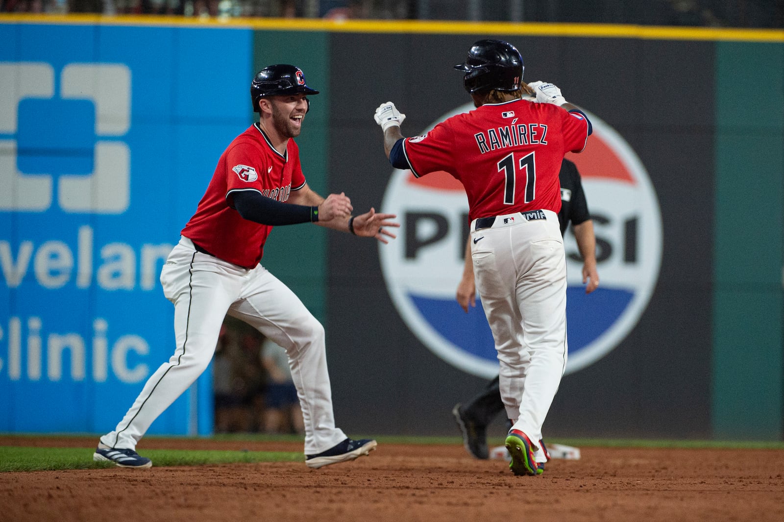 Cleveland Guardians' David Fry, left, congratulates Jose Ramirez (11) for his game winning single at the end of the 10th inning of a baseball game against the Toronto Blue Jays, Wednesday, June 25, 2025, in Cleveland. (AP Photo/Phil Long)