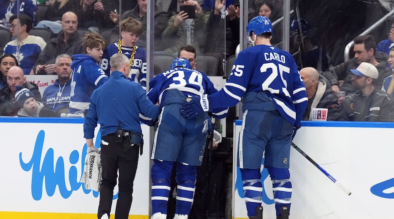 Toronto Maple Leafs Auston Matthews (34) is helped off the ice after being injured by Anaheim Ducks Radko Gudas during the second period of an NHL hockey game in Toronto, Thursday, March 12, 2026. (Nathan Denette/The Canadian Press via AP)
