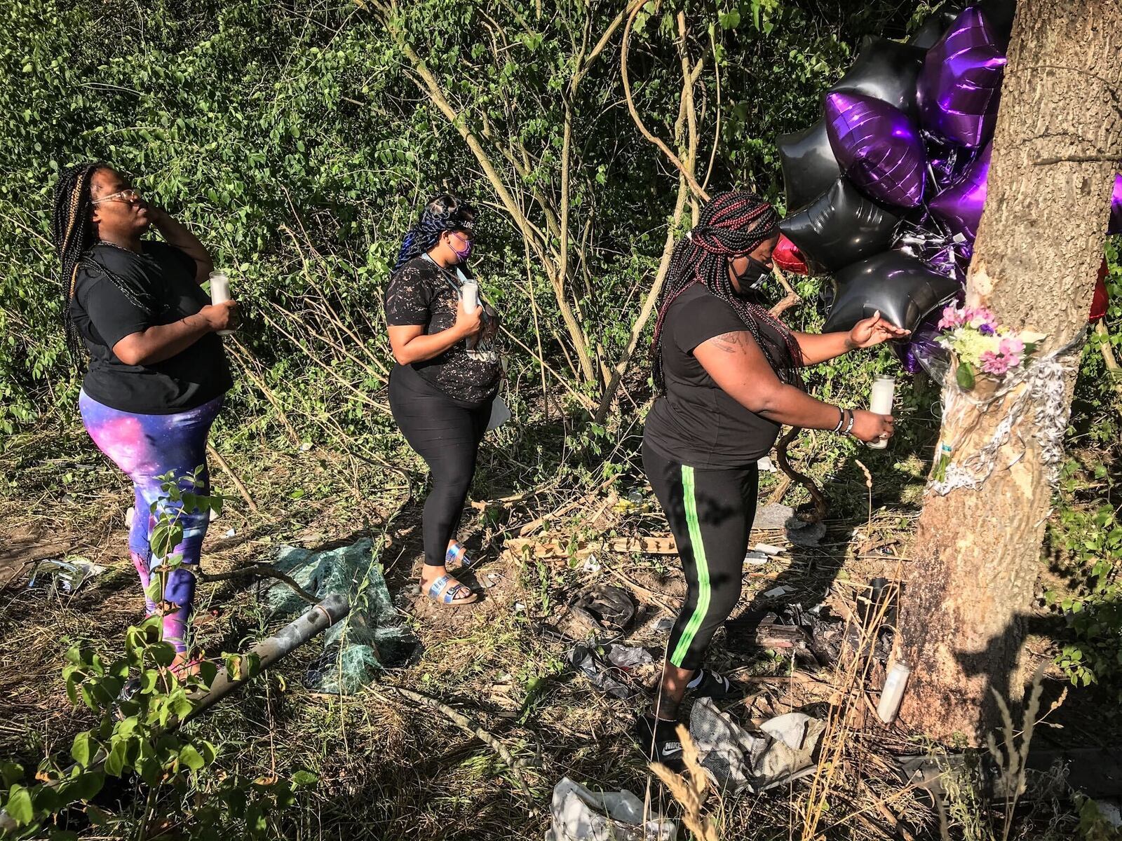 Mourners Talisha Hawkins, Natasha Sutton and Kasaundra Moreland light a candle at the crash site where their friend Leah Smith, 35, of Dayton, was killed Wednesday night, July 15, 2020. Smith's 3-year-old son survived the crash after their car was struck by another car at the intersection of Olive and Little Richmond roads in Trotwood. Two teens in the other vehicle also did not survive. JIM NOELKER/STAFF