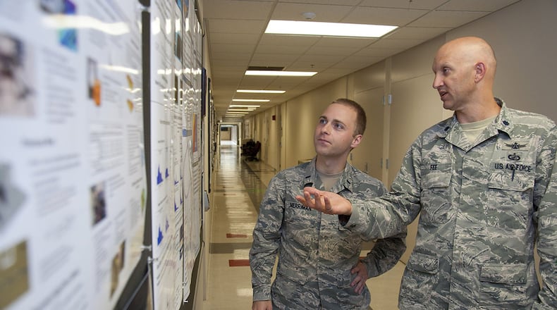Lt. Col. James Fee, Air Force Institute of Technology assistant professor of nuclear engineering, discusses electromagnetic pulse and how to model it from a nuclear weapon with 1st. Lt. Cameron Merriman, an AFIT student, June 22 using a display board hung in one of AFIT’s corridors. (U.S. Air Force photo/John Harrington)