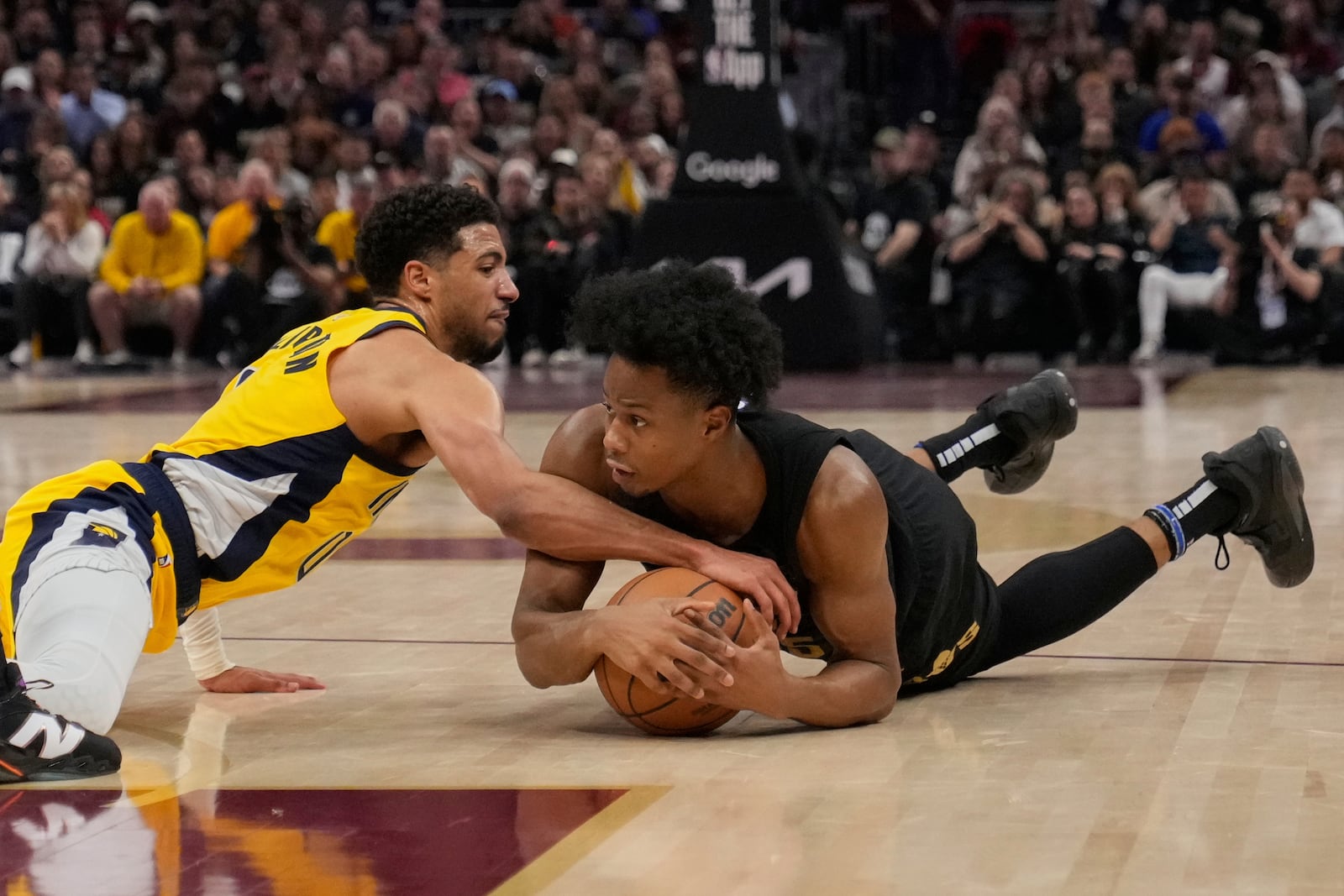 Indiana Pacers guard Tyrese Haliburton, left, and Cleveland Cavaliers forward Isaac Okoro scramble for a loose ball during the first half in Game 5 of an Eastern Conference semifinal NBA basketball playoff Tuesday, May 13, 2025, in Cleveland. (AP Photo/Sue Ogrocki)