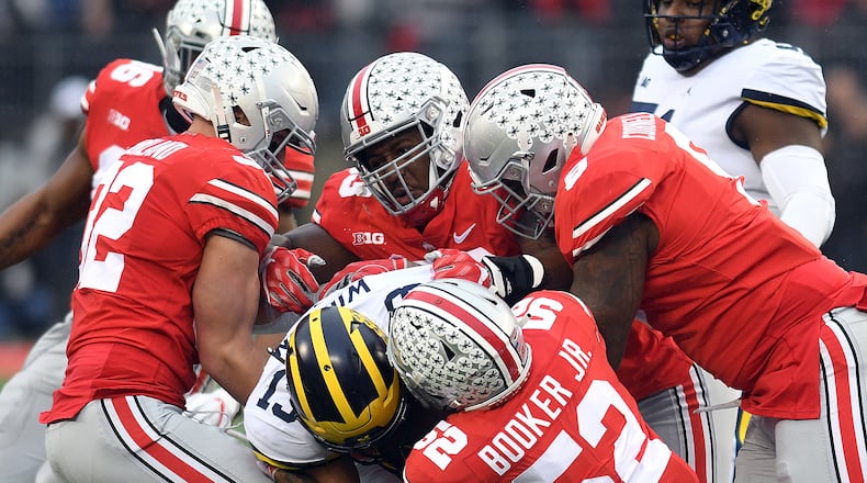 Several Ohio State defenders take down Michiganâs Tru Wilson during the first half of Saturdayâs game at Ohio Stadium. Nick Falzerano/CONTRIBUTED