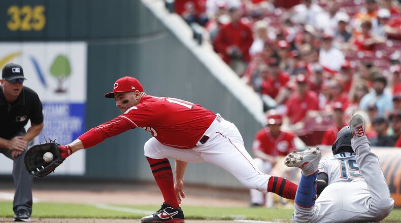 Miguel Rojas of the Marlins dives at first base ahead of the throw to Joey Votto of the Reds after hitting a line drive off of pitcher Sonny Gray in the second inning at Great American Ball Park on Thursday. (Photo by Joe Robbins/Getty Images)