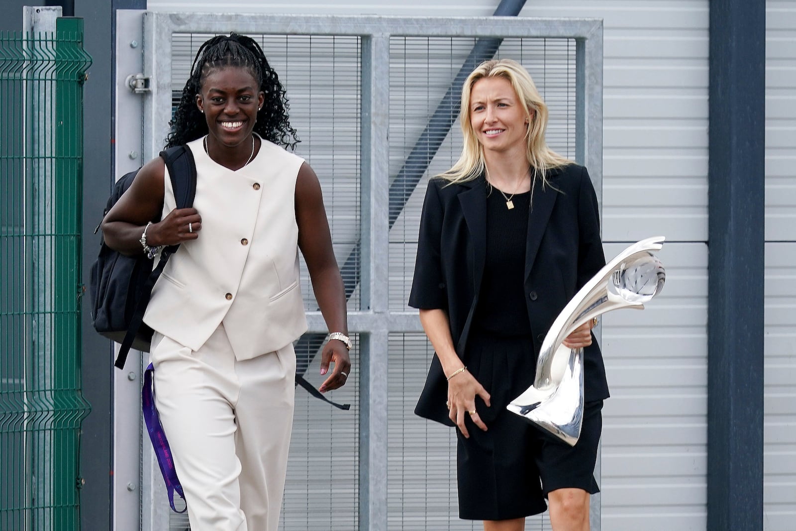 England's Leah Williamson, right, holds the Euro 2025 trophy as she heads to greet fans with Michelle Agyemang after arriving at London Southend Airport in Southend, England, Monday, July 28, 2025, after they won the Women's Euro 2025 final. (Yui Mok/PA via AP)