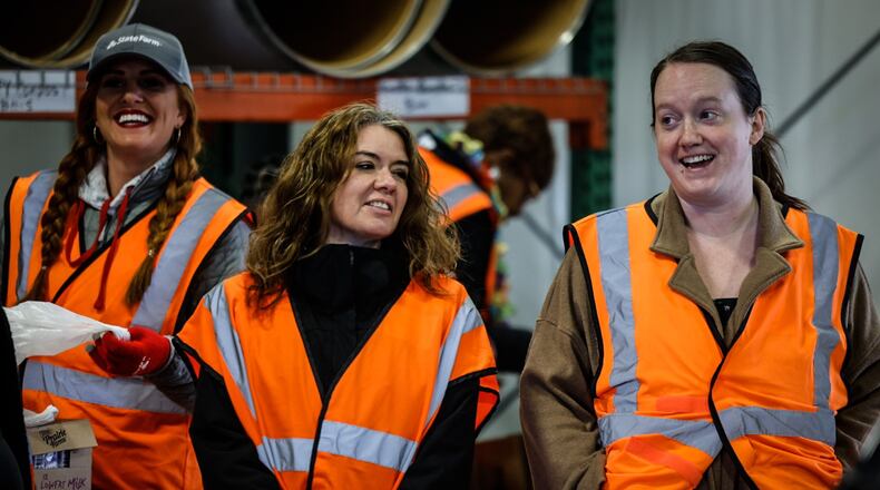 Dayton Daily News reporter, Aimee Hancock, right, helps other volunteers load food into vehicles Thursday morning November 17, 2022 at the Dayton Foodbank. JIM NOELKER/STAFF