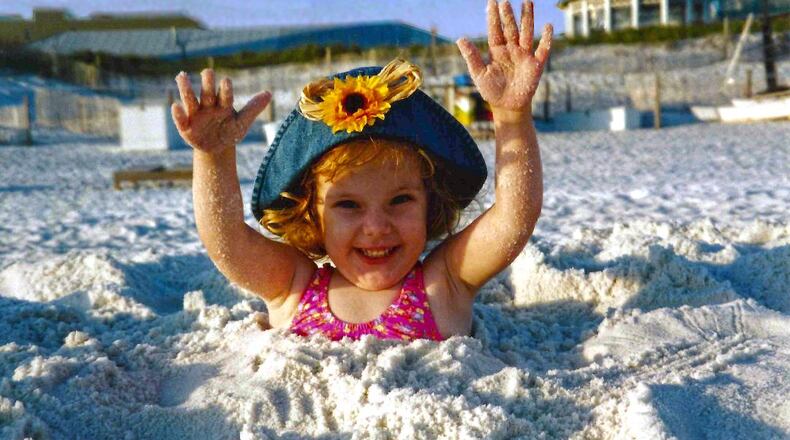 Three year old Caleigh Hildebrandt has some fun buried in the sand on the beach in Destin, Florida. The photo is now etched in granite and appears on the back on her grave memorial. CONTRIBUTED