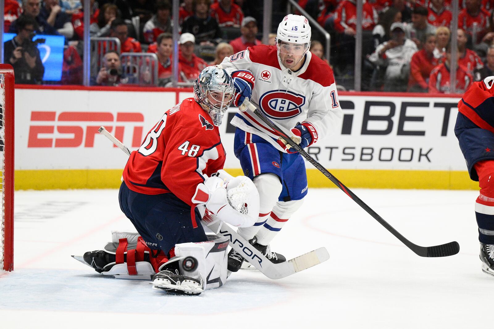 Montreal Canadiens center Alex Newhook (15) and Washington Capitals goaltender Logan Thompson (48) battle for the puck in the second period of Game 1 of a first-round NHL hockey playoff series Monday, April 21, 2025, in Washington. (AP Photo/Nick Wass)