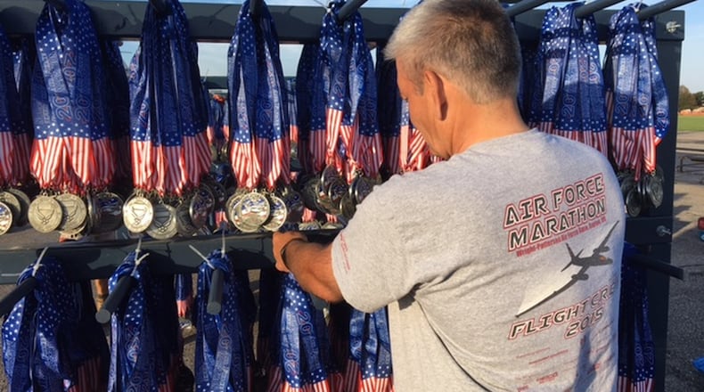 Air Force Marathon volunteer Brian Childers, of Portsmouth, hangs race day medals at the finish line at the National Museum of the U.S. Air Force in September 2016. BARRIE BARBER/STAFF FILE PHOTO
