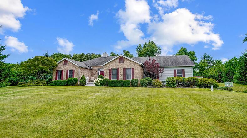 The front of the split floorplan brick and vinyl ranch has a three car attached garage and wooden front porch.