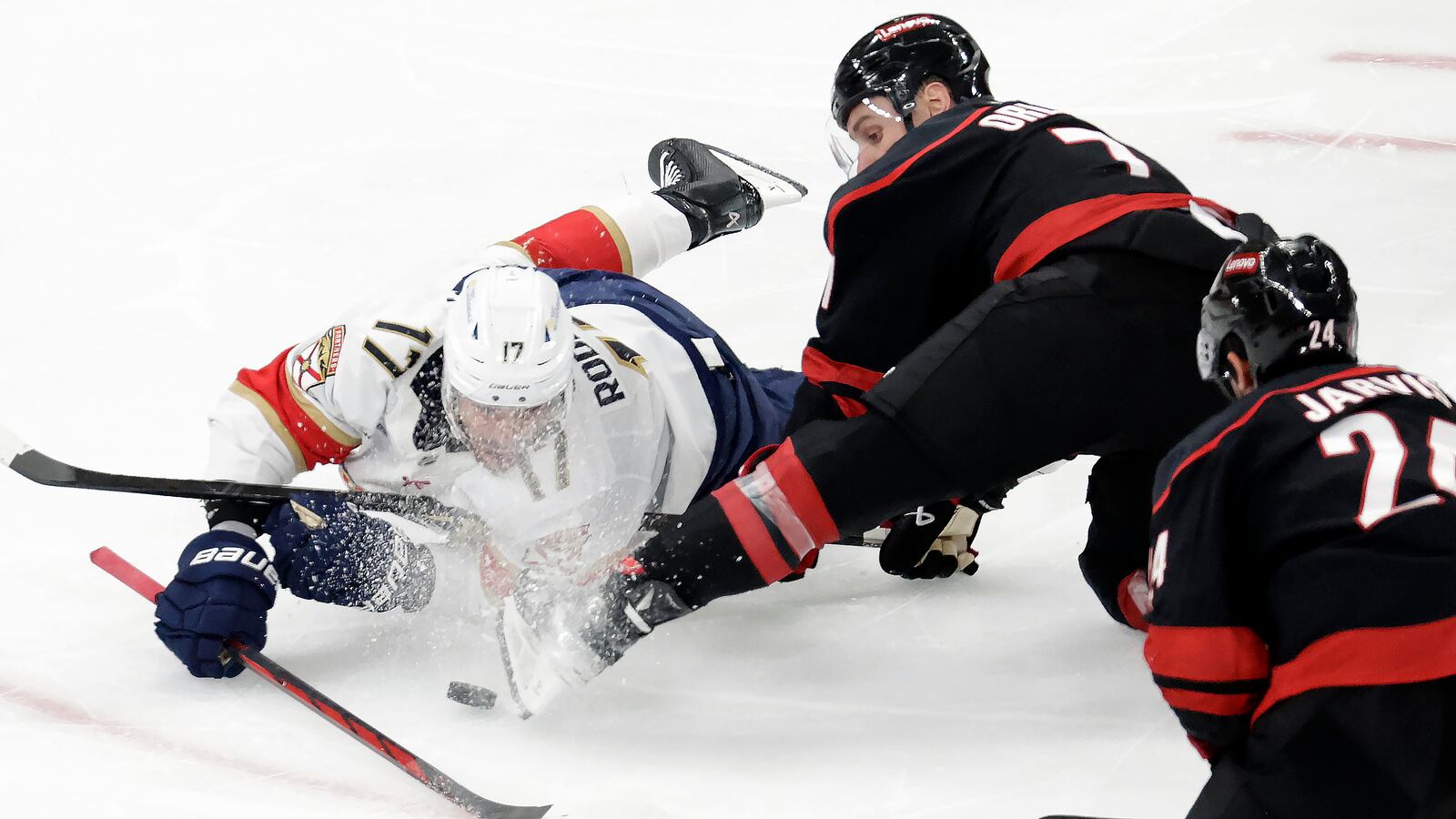Florida Panthers center Evan Rodrigues (17) and Carolina Hurricanes defenseman Dmitry Orlov (7) battle for the puck during the third period of Game 5 of the NHL hockey Stanley Cup Eastern Conference finals Wednesday, May 28, 2025, in Raleigh, N.C. (AP Photo/Chris Seward)