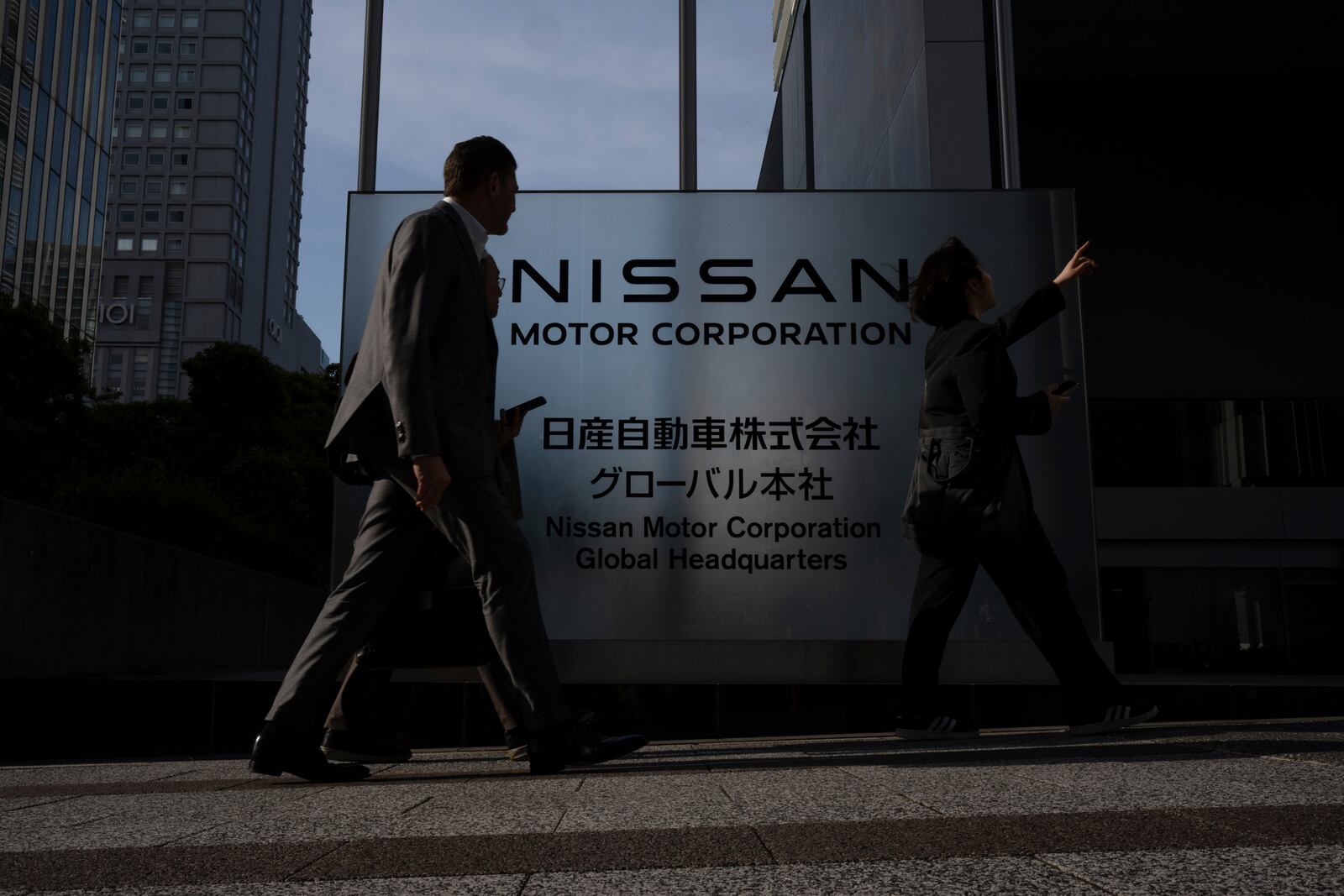 Visitors walk past Nissan signage at Nissan headquarters in Yokohama, Tuesday, May 13, 2025. (AP Photo/Louise Delmotte)