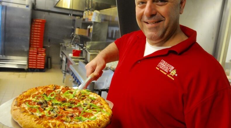 Tom Jarbo an employee at Happy’s Pizza on Salem Avenue pulls a pizza from the oven at their newly opened business. STAFF/MARSHALL GORBY