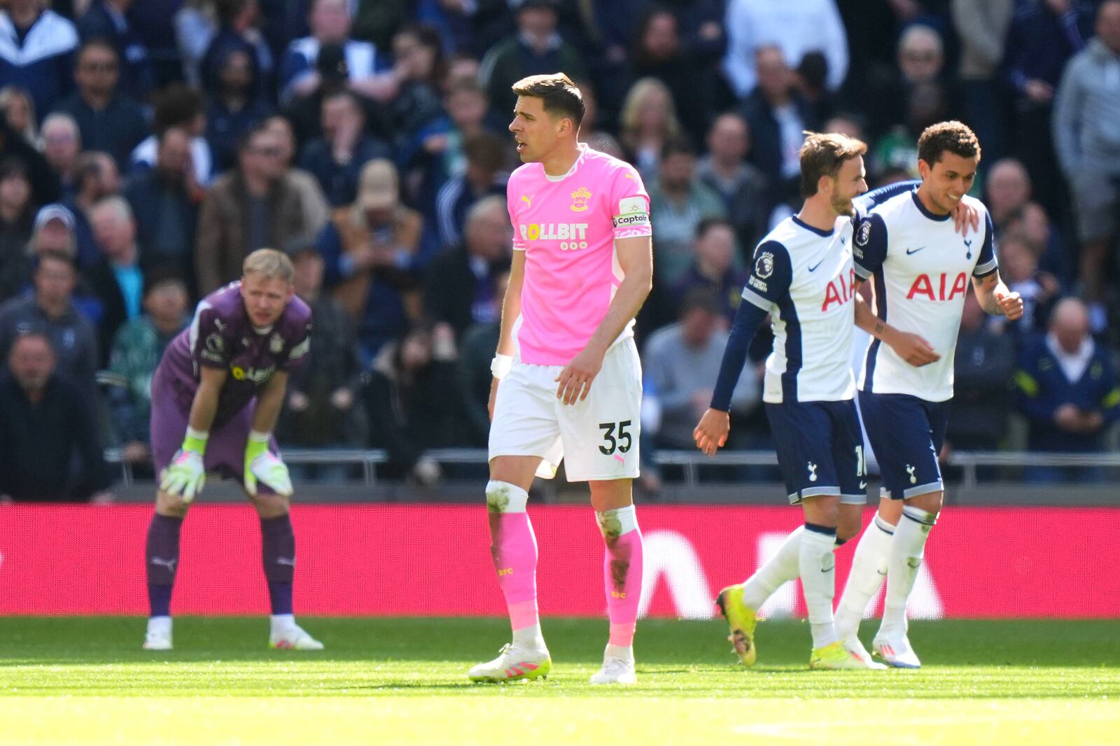 Southampton goalkeeper Aaron Ramsdale, background left and Jan Bednarek foreground react after Tottenham Hotspur's Brennan Johnson, right, scored his side's second goal of the game as he celebrates with teammate James Maddison, during the English Premier League soccer match between Tottenham Hotspur and Southampton at Tottenham Hotspur Stadium, in London, Sunday April 6, 2025. (Bradley Collyer/PA via AP)